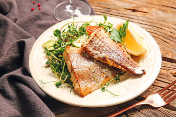 Plate with tasty baked cod fillet and vegetables on wooden background, closeup