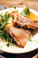 Plate with tasty baked cod fillet and vegetables on table, closeup