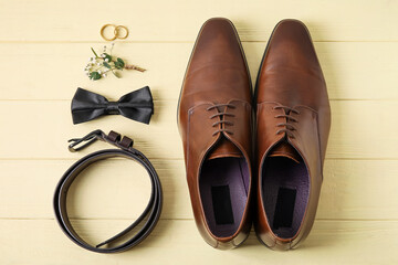 Wedding rings and stylish groom accessories on color wooden background