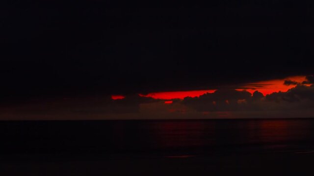 Timelapse of dramatic sunset, red hole in dark clouds, Plage la Salie