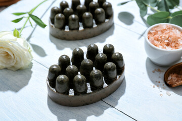 Massage soap bars, sea salt and flower on light wooden background, closeup