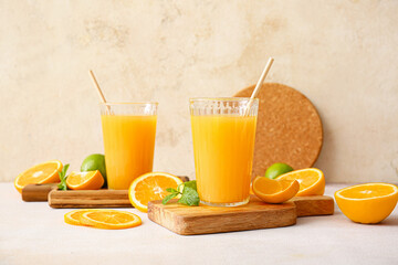 Glasses of tasty orange juice on light background