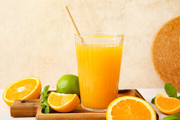 Board with glass of tasty orange juice on light background
