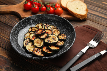 Plate with tasty grilled zucchini on wooden background