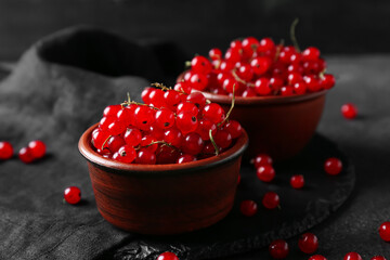 Bowls with fresh red currants on dark background, closeup