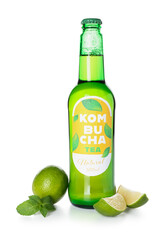 Bottle of natural kombucha tea and fresh lime on white background
