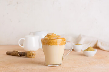 Glass cup of tasty dalgona hojicha latte on table