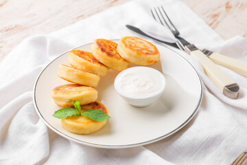 Plate with cottage cheese pancakes and sour cream on table, closeup