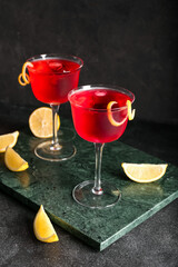 Glasses of tasty cosmopolitan cocktail on dark background