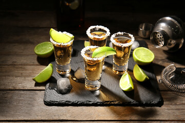 Shots of tasty tequila with lime on wooden background