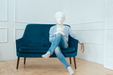 Man sitting on the sofa and holding white gypsum head of a woman