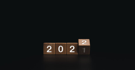 2022 Happy New year welcome and Merry Christmas banner. Flipping wooden cube blocks for changing the year from 2021 to 2022 on dark background.