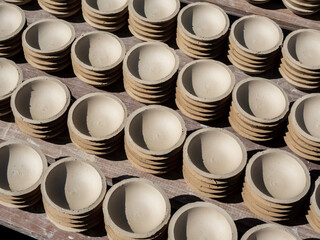 Many small plates, round shape made by ceramic clay and dried with sunshine. Earthenware process manufacturing.