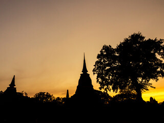 Obraz premium Amazing scenetic of silhouette of pagoda, temple and gold sunset sky in Sukhothai Historical Park, a UNESCO World Heritage Site in Thailand.