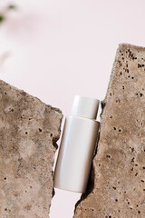 White blank bottle of cosmetic product between grey pieces of concrete material