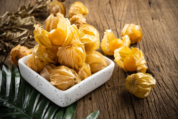 Cape Gooseberry in a white cup rests on an old wood floor