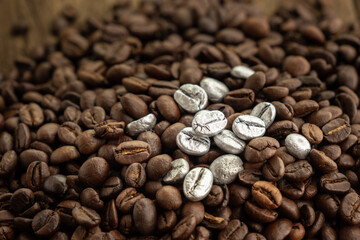 Silver coffee beans on a pile of coffee beans. The concept of luxury is extraordinary