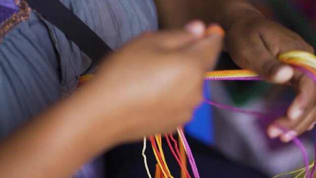 Mexican regional embroidery. Latina merchant weaving colored figures in Chiapas, Mexico