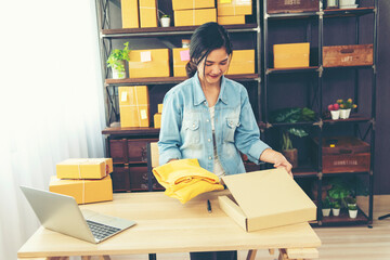 Woman packing box on table checking goods package delivery shipping to customer. Asian woman startup small business at home office desk. Entrepreneur asian woman packing product for delivery items