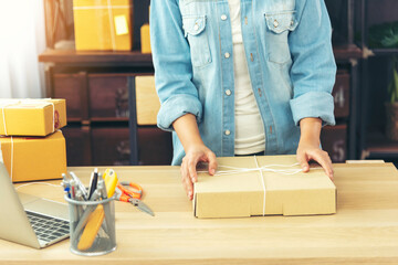 Woman packing box on table checking goods package delivery shipping to customer. Asian woman startup small business at home office desk. Entrepreneur asian woman packing product for delivery items