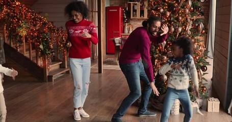 Festive happy african american couple parents dancing with energetic laughing little in decorated living room near Christmas tree, celebrating New year, joyful family winter holidays disco pastime.