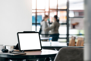 Mockup blank screen tablet on wooden table in cafe with blurred people on background.