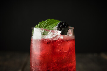Blackberry cocktail with crushed ice on the rustic wooden background. Selective focus. Shallow depth of field.
