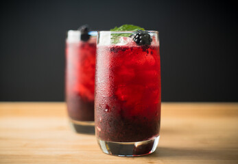 Blackberry cocktail with crushed ice on the rustic wooden background. Selective focus. Shallow...