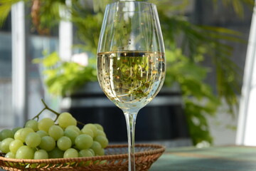 A glass of white wine with grapes on wooden table. White wine Riesling, from white grapes
