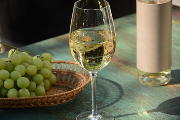 A glass of white wine with grapes on wooden table. White wine Riesling, from white grapes
