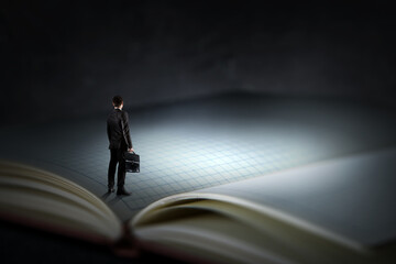 Young businessman standing on a huge book