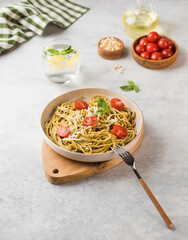 Spaghetti pasta with pesto sauce and cherry tomatoes on a plate. Menu, Italian cuisine.