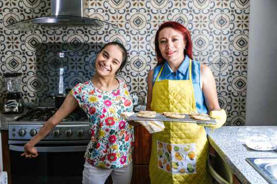Latin mother and her teenage daughter with cerebral palsy in the kitchen baking cookies in Latin America Disability concept