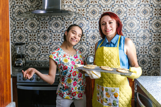 Latin mother and her teenage daughter with cerebral palsy in the kitchen baking cookies in Latin America disability concept