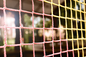 Kids playground safety net close up. Adventure part abstract blurred background.