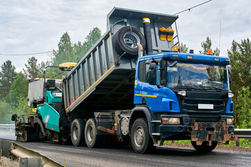 unloading of asphalt into an asphalt paver and laying of asphalt with the help of an asphalt paver