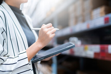 close up female business owner hand hold tablet device checking inventory stock at shop warehouse...