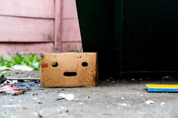 An old cardboard box on the trash. The box has holes in the form of a sad face. Ecology. Pollution of the planet