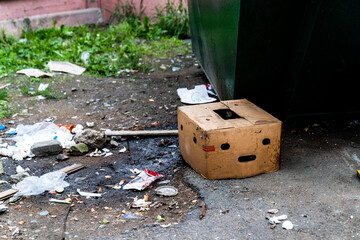 An old cardboard box on the trash. The box has holes in the form of a sad face. Ecology. Pollution of the planet