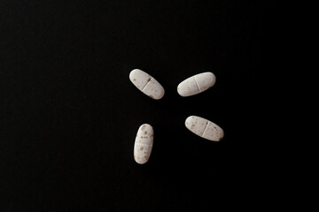 White spoiled pills covered with mold. Pills on a black background. The expiration date has expired. Top view