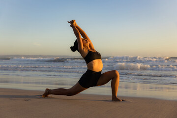 Sunset beach yoga. Anjaneyasana, Low Lunge Pose. Crescent Moon Pose. Lunging back bending asana. Supporting muscle. Flexible spine and back. Copy space.  Yoga retreat. Seminyak beach, Bali