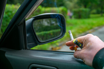 a smoking cigarette with a filter in the hand of the driver car