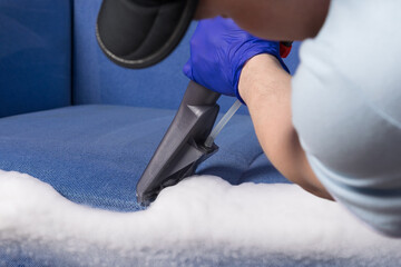 in the hands of an employee of a cleaning company, the vacuum cleaner collects foam for dry cleaning of upholstered furniture
