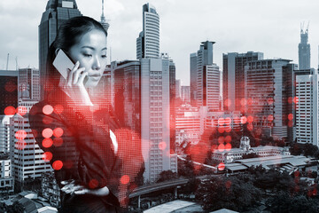 Fototapeta premium Attractive Asian businesswoman processing conference call to develop social media marketing strategy to achieve business goals. Hologram icons over Kuala Lumpur background.