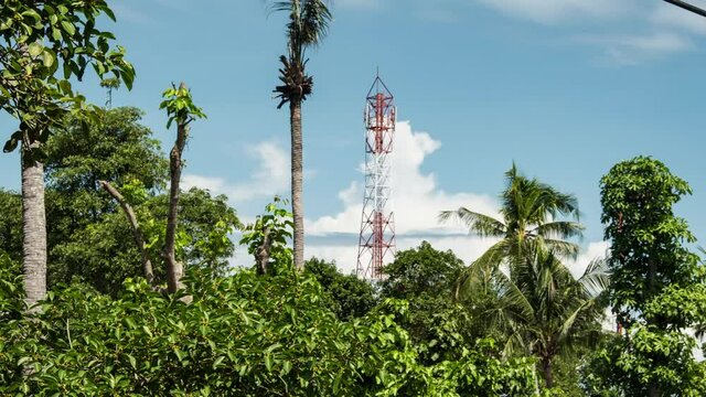4K Time-lapse footage of tele-communication tower with green lush foliage and fast moving couds