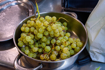 a large bunch of white grapes in a casserole on a kitchen table next to other kitchen utensils