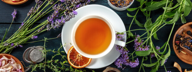Tea panorama with herbs, flowers and fruit, shot from the top on a dark rustic wooden background