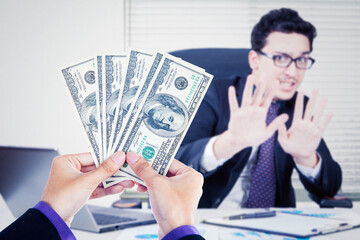 Young businessman refusing bribe money in office