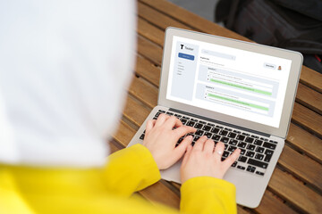 Back view of a muslim woman in hijab using laptop in cafe