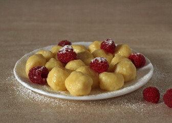 Homemade cheesecakes with balls of cottage cheese with fresh raspberries on a light background with powdered sugar